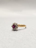 Gold ring with white gold settings holding a diamond halo and Ruby centre stone