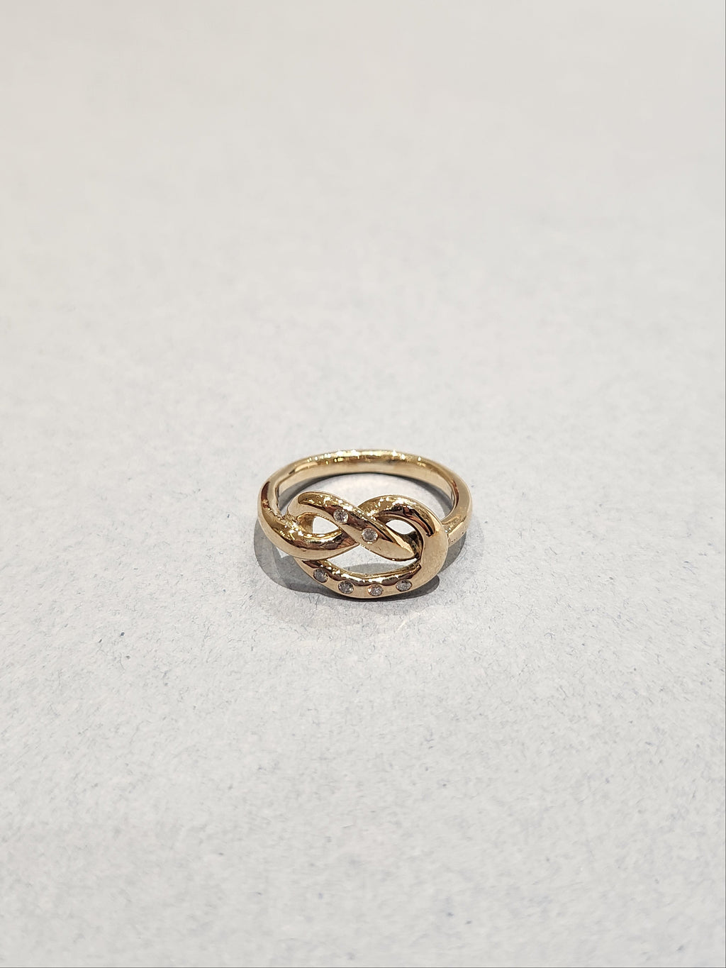 Gold ring in a knotted design, with 6
Round Diamonds flush set into the gold. 9ct Yellow gold. Pretzel ring.  Top view of ring. 