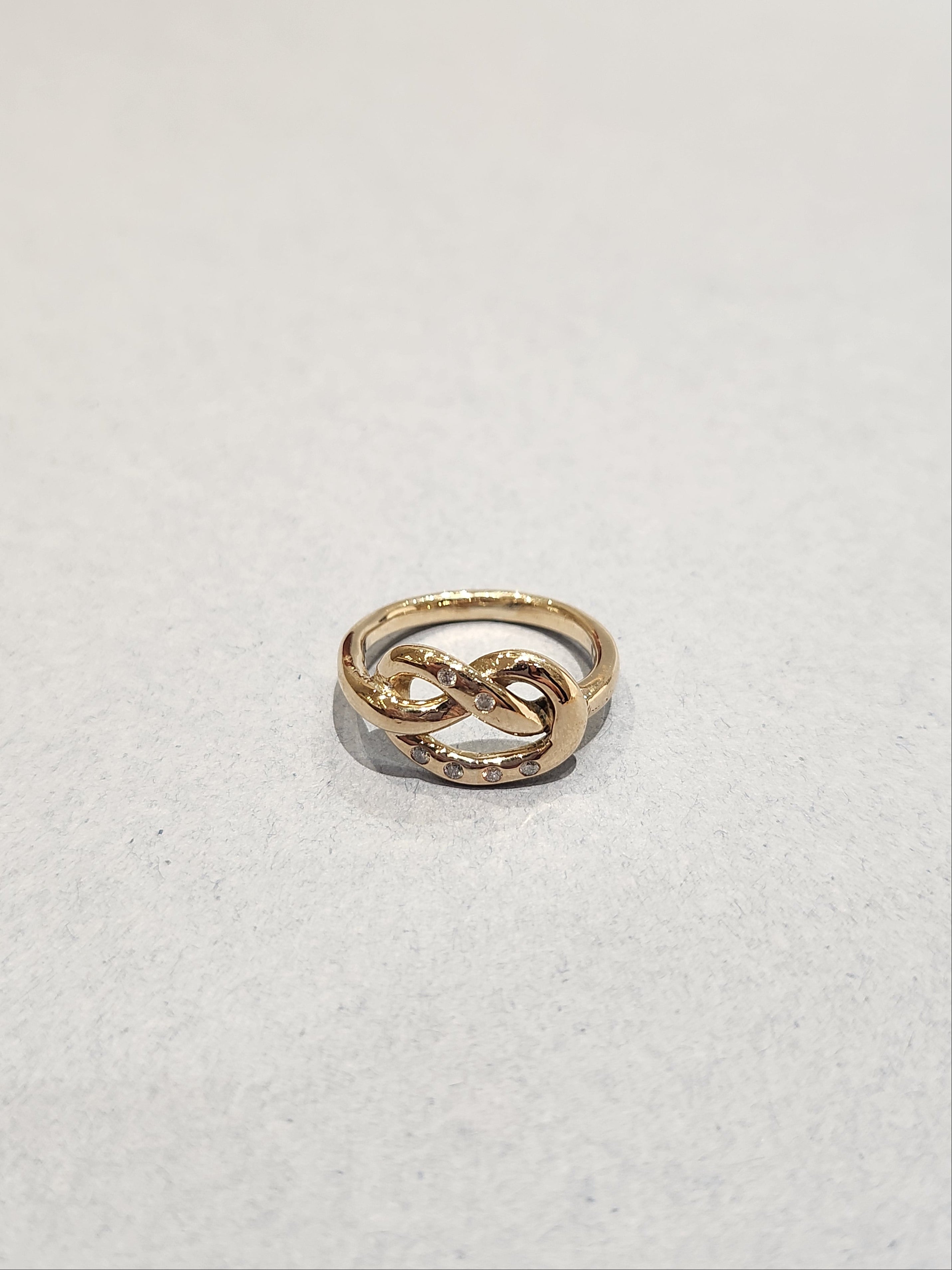 Gold ring in a knotted design, with 6
Round Diamonds flush set into the gold. 9ct Yellow gold. Pretzel ring.  Top view of ring. 