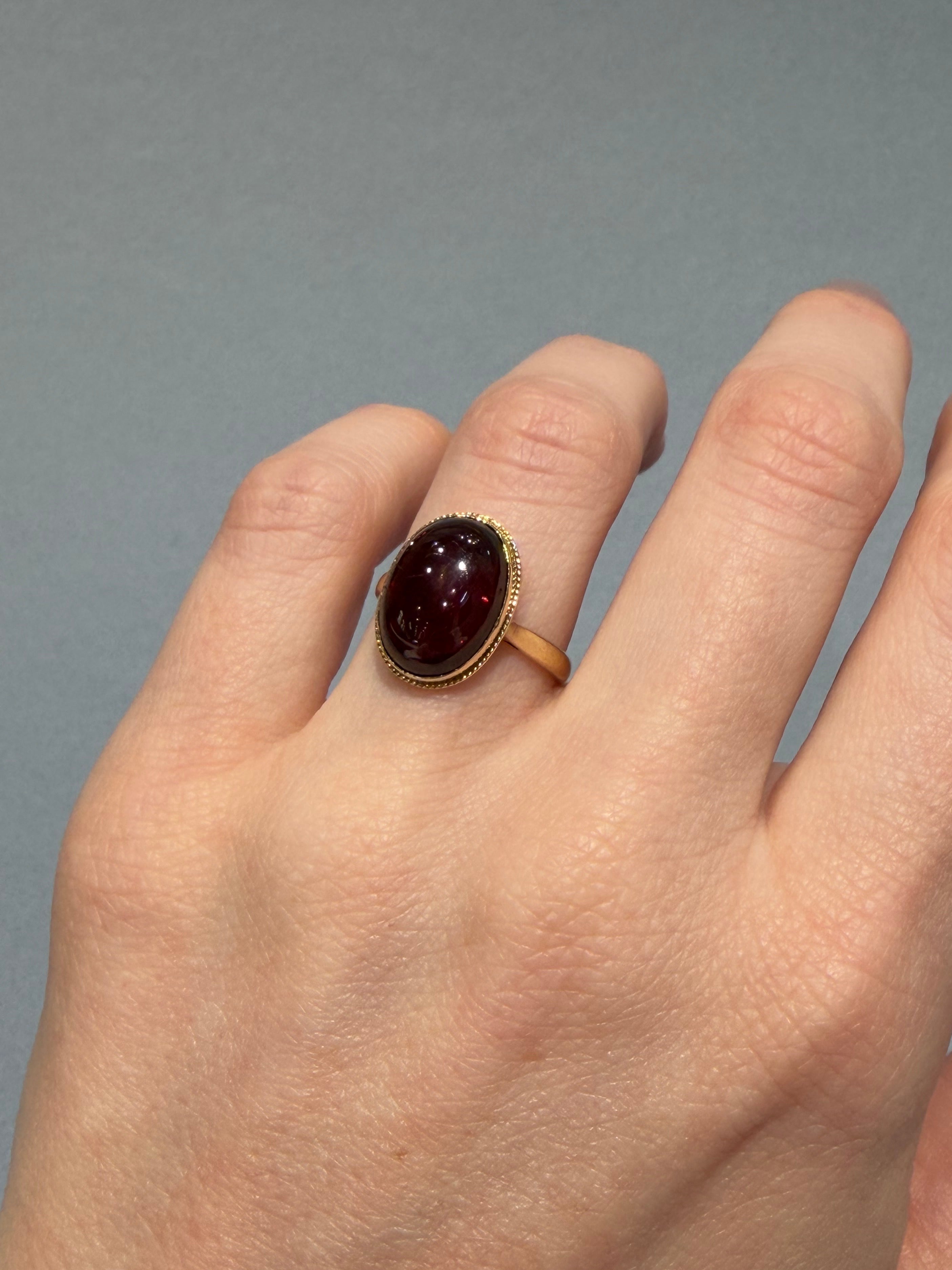9ct Yellow gold and cabochon garnet ring on a hand.