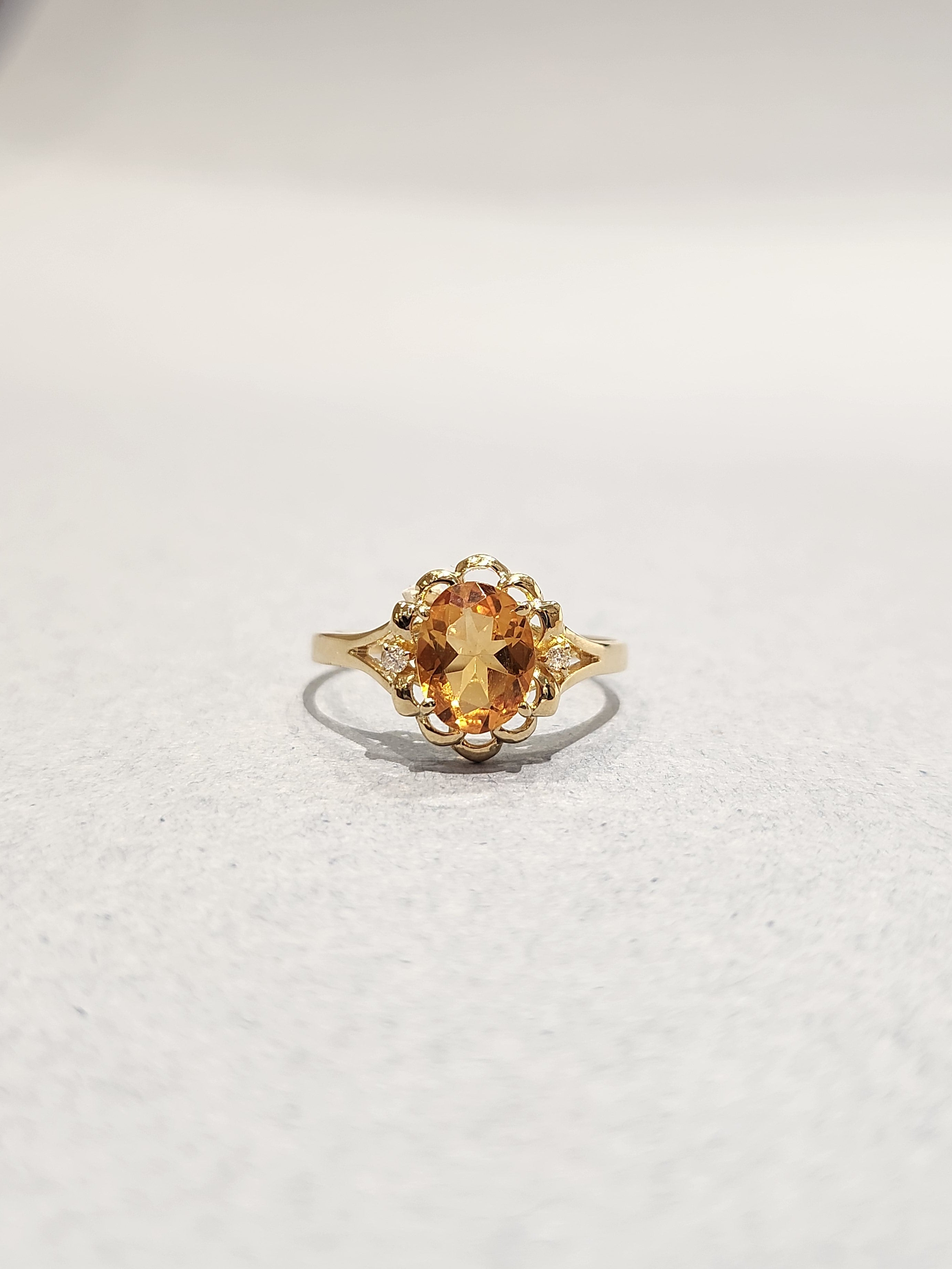 Gold ring with ornate gold work and large orange oval centre stone with 2 diamond side stones