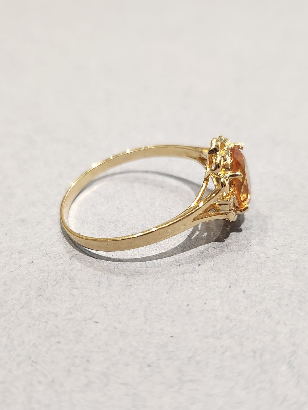 Side view shot of Gold ring with ornate gold work and large orange oval centre stone with 2 diamond side stones