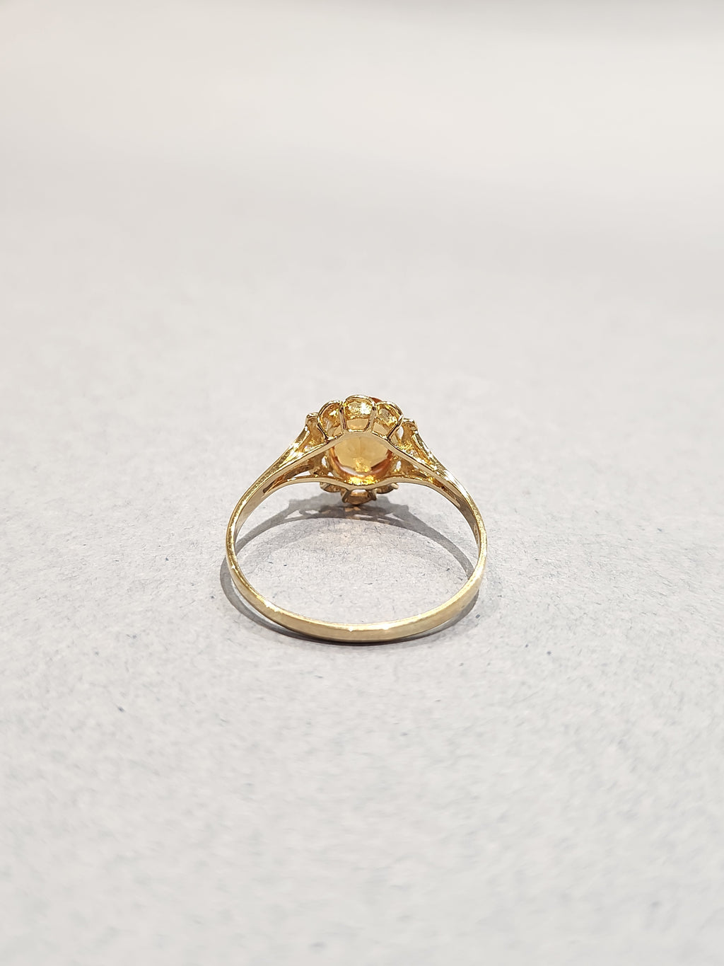 Rear view shot of Gold ring with ornate gold work and large orange oval centre stone with 2 diamond side stones showing underside of setting